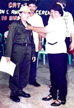 A young woman in an ROTC-style uniform smiles at the camera