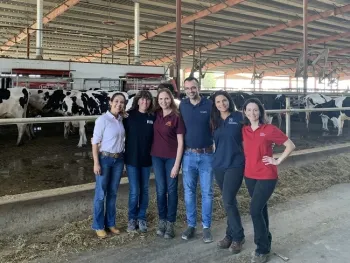 Thaisa Marques, investigadora de post doctorado de UC Davis, Shonda Reid, gerente de la lechería Rau; Marcia Endres, profesora de la Facultad de Veterinaria de la Universidad de Minnesota; Fabio Lima, profesor de la Facultad de Veterinaria de UC Davis; Daniela Bruno, asesora de lecherías de UCCE y Camila Lage, ex investigadora de post doctorado de UC Davis posan frente a uno de los establos libres de la lechería Fred Rau. Dos de los robots de ordeño se pueden observan detrás de ellas. Fotografía