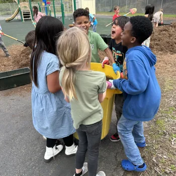 A group of kids carrying a bucket.