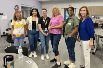 Uno de los participantes del programa MORE sostiene una raíz de haba para mostrar sus nódulos de nitrógeno, durante su visita al huerto del campus. Fotografía por Tracy Celio