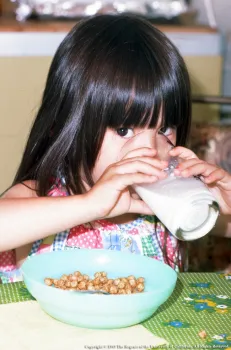 Toddler-age girl drinking milk from a glass.
