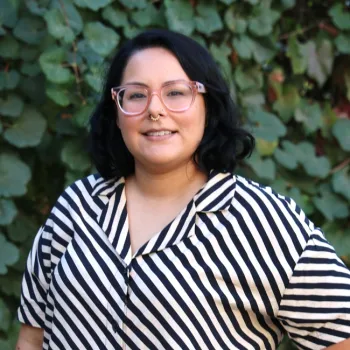 Woman with dark hair and glasses in a striped top