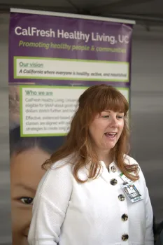 Mary Ann Mills stands in front of a CalFresh Healthy Living banner