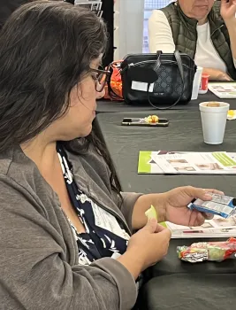 Adult EFNEP participant eating an apple slice while reading the nutrition facts for a snack.