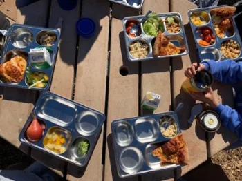 School lunch served on stainless steel reusable trays.]