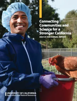 A man wearing a hairnet and lab coat is holding a chicken