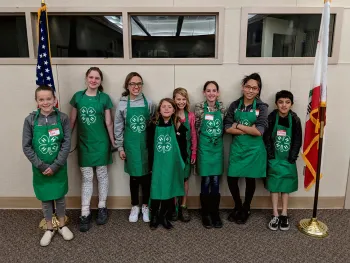 4-H youth wearing aprons between California and USA flags.