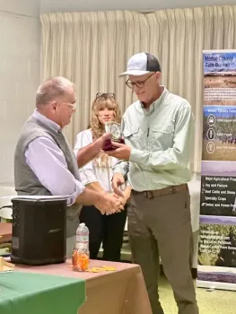 A man hands David a fancy clock as a woman in back observes