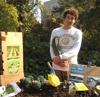 Houston Wilson in a California sweatshirt stands at a table sharing bounty of the Gill Tract