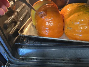 Pumpkin cut in half on baking sheet in oven