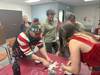 Two people across a table compete in a game to gather marshmallows 