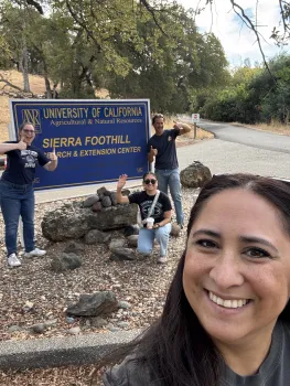 Four people ham it up next to the Sierra Foothill REC sign