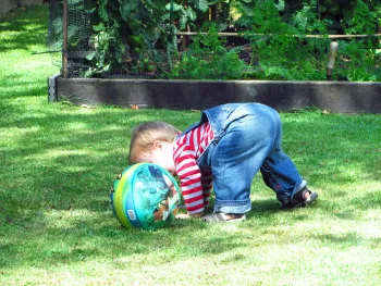 kid playing with a ball on a lawn