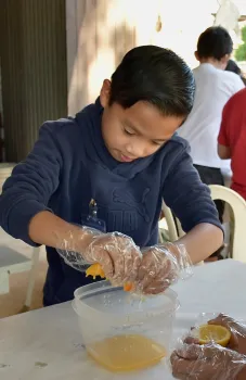 Youth squeezes the juice out from a piece of orange.