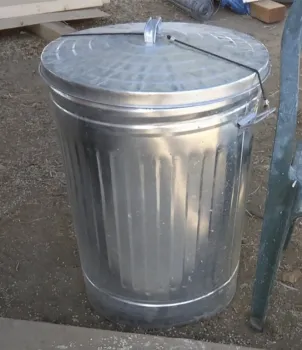 A bungy cord secures the lid to a metal garbage can 