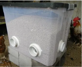A boxy feeder with a lid sits atop cinder blocks