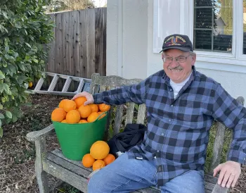 Earl Weak sits on a bench next to oranges from his home tree.