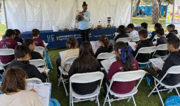 🧠 Learning Through Observation and Participation 📝 [INSERT IMAGE 4: STUDENTS WITH WORKSHEETS] Alt text: Students seated under a tent writing observations on worksheets during a water treatment activity.