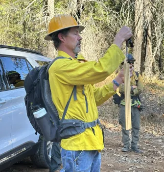 A person assessing fuel moisture using 10-hour fuel sticks.