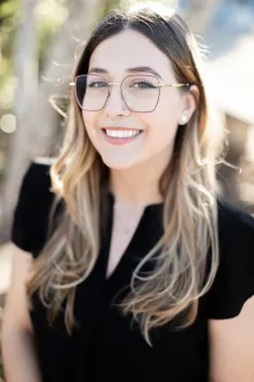 White woman with long blonde hair, glasses, black shirt, smiling