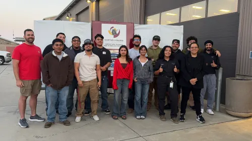 A farm robotics team stands in front of a backdrop that reads Hartnell College