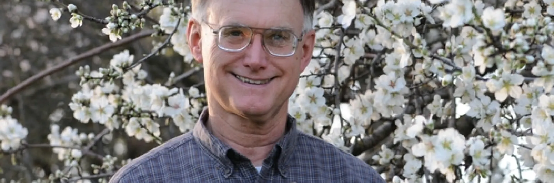 APICULTURIST ERIC MUSSEN stands amid the almond blossoms at the Harry H. Laidlaw Jr. Honey Bee Research Facility at UC Davis. He is the 2010 winner of the statewide Pedro Ilic Outstanding Agriculture Educator. (Photo by Kathy Keatley Garvey)