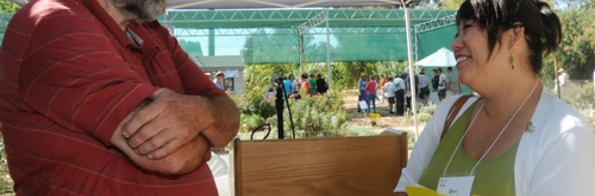 BEEKEEPER Frank Pendell of Pendell Apiaries, Stonyford, Calif., vice president of the California State Beekeepers' Association, chats with Dori Sera Bailey, director of consumer communications, Häagen-Dazs and Dreyer’s Grand Ice Cream. In the back are visitors touring the garden. (Photo by Kathy Keatley Garvey)