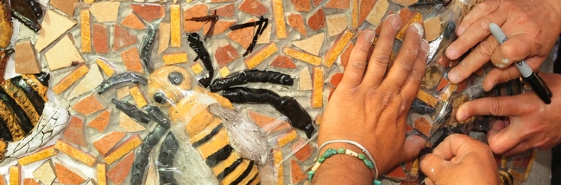 Multiple hands at work on the mosaic ceramic panels. (Photo by Kathy Keatley Garvey)