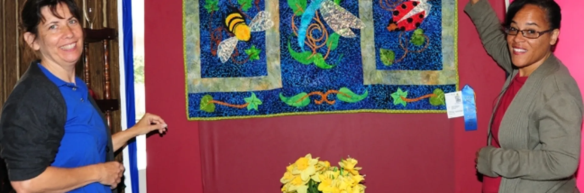 Gloria Gonzalez (left) of Vallejo, superintendent of McCormack Hall, Solano County Fair, and assistant Iris Mayhew of Vallejo hang a quilt by LaQuita Tummings of Vallejo. (Photo by Kathy Keatley Garvey)