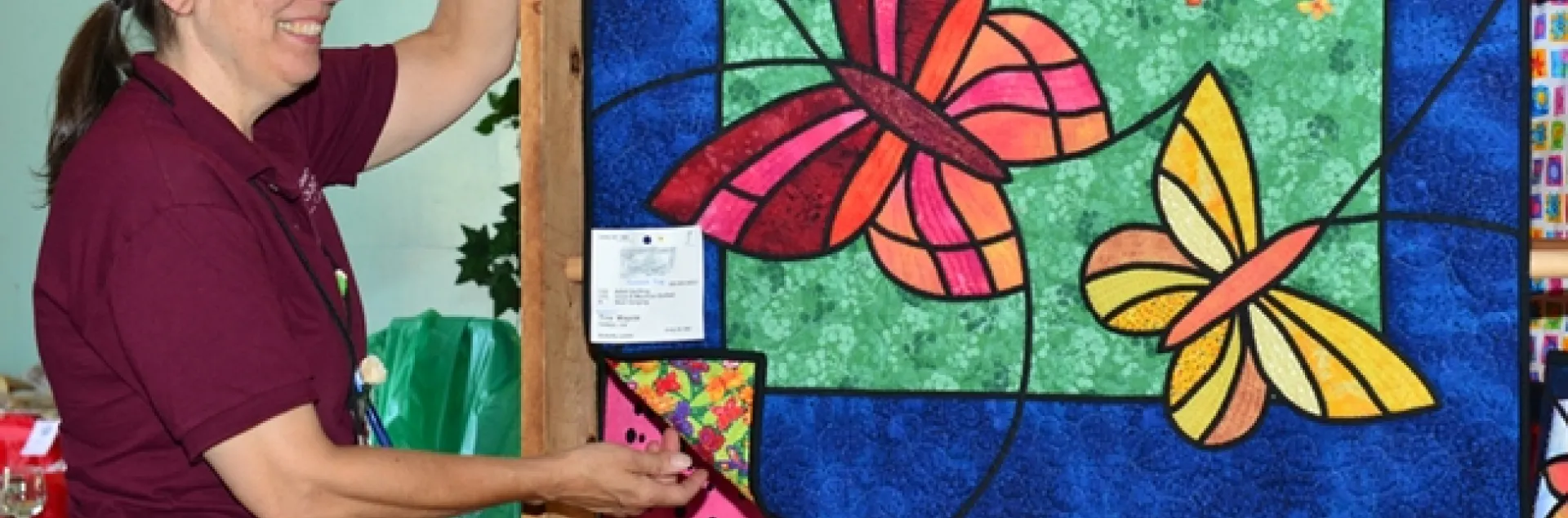 McCormack Hall superintendent Gloria Gonzalez hangs "Butterfly Lovers" by Tina Waycie of Vallejo. (Photo by Kathy Keatley Garvey)