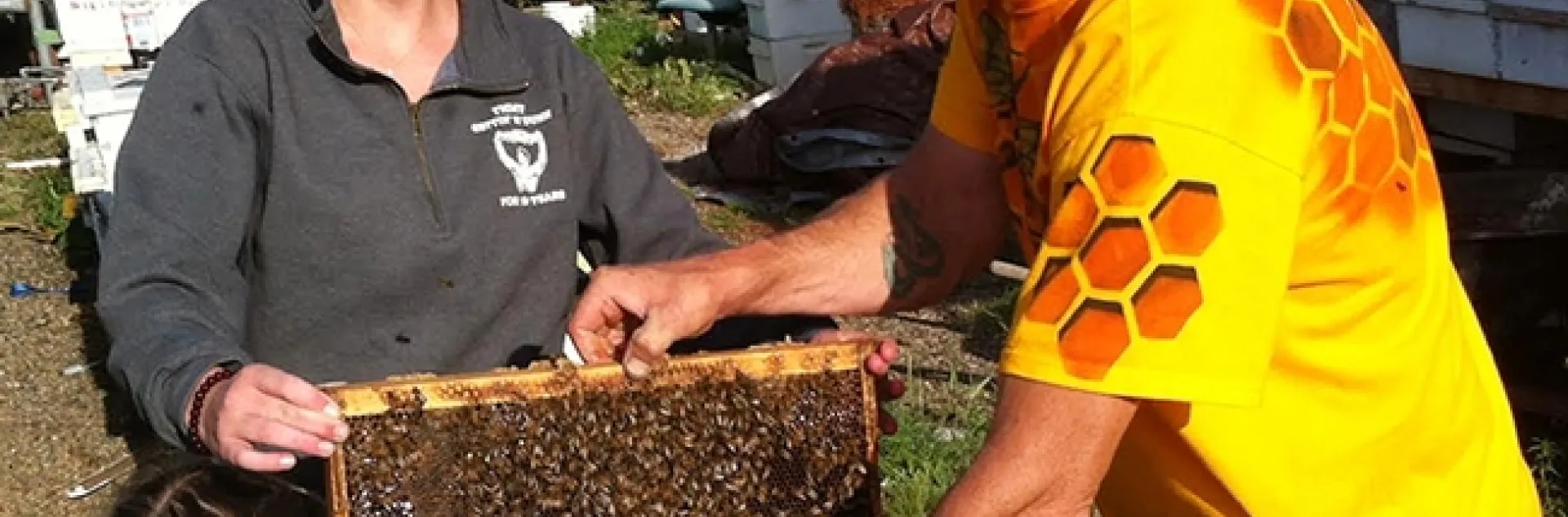 Beekeeper Brian Fishback helping Sheridan Miller with her hive. (Photo by Craig Miller)