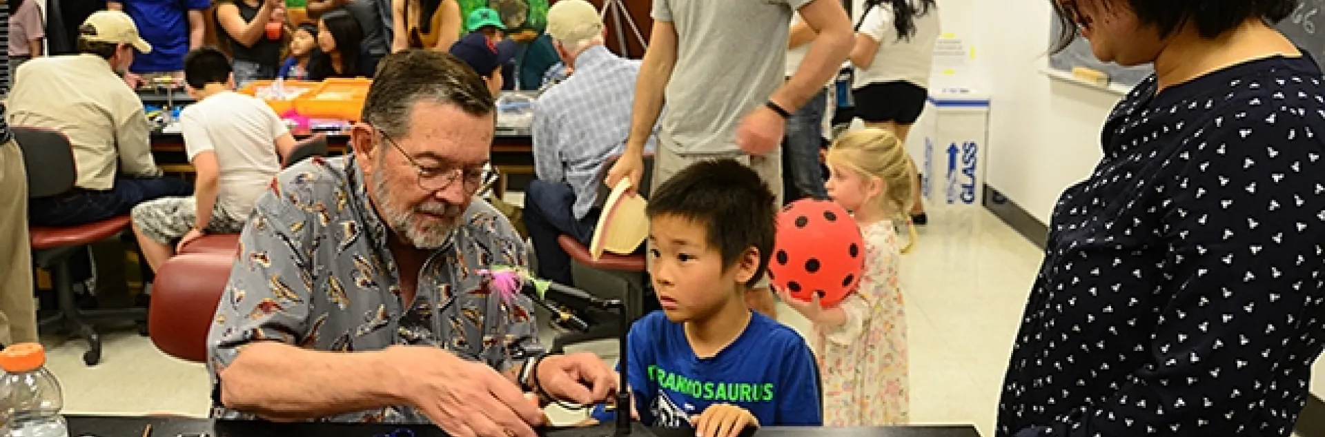 While mom (right) observes, Steven Mao, 7, of Davis, watches Dave Driscoll of the Fly Fishers of Davis tie a fly during the 104th annual UC Davis Picnic Day. (Photo by Kathy Keatley Garvey)