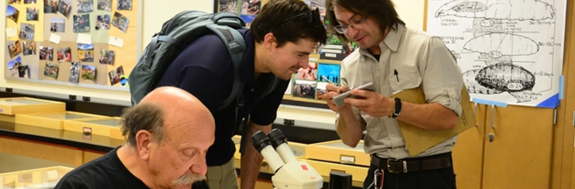 Forensic entomologist Robert Kimsey (foreground) works on his project at his Dr. Death table in 122 Briggs Hall, while doctoral candidate Brendon Boudinot (right) answers a question from a visitor. Kimsey and Boudinot co-chaired the Briggs Hall Picnic Day activities that won the campuswide best exhibit in the "One with Nature" category. (Photo by Kathy Keatley Garvey)
