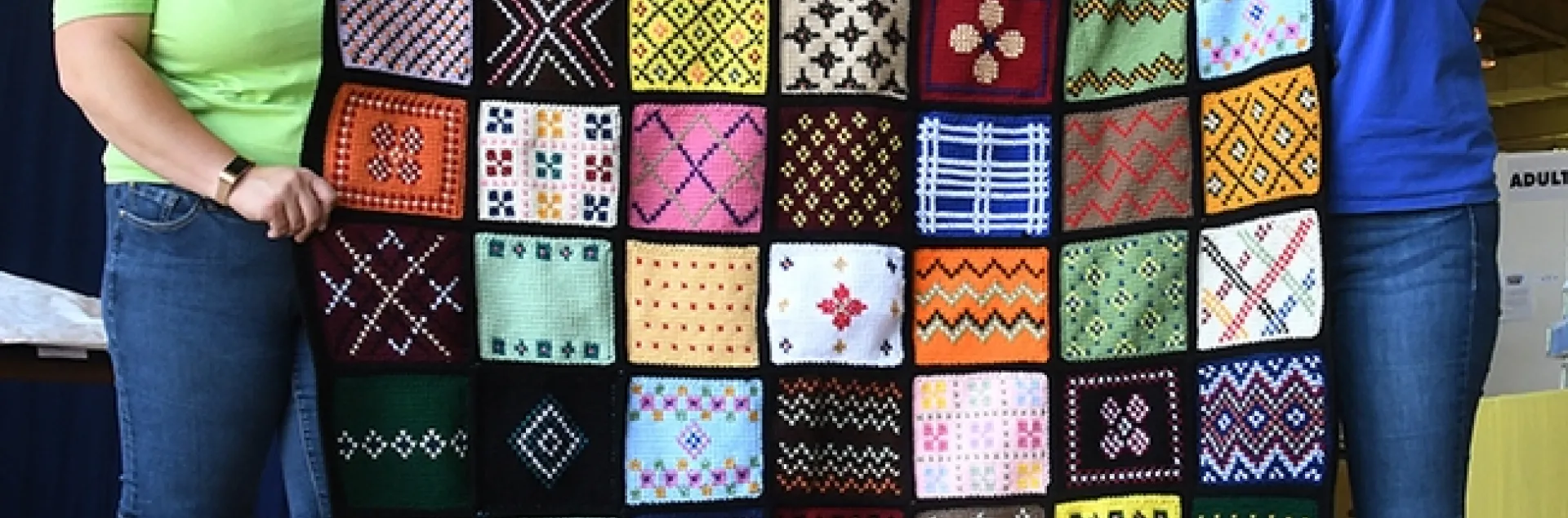 See the bumble bee on the aghan (top row)? This Minnesota sample afghan is the work of Debra Holter of San Pablo. Holding it are McCormack Hall superintendent Gloria Gonzalez (right) and assistant Kara Payne. (Photo by Kathy Keatley Garvey)