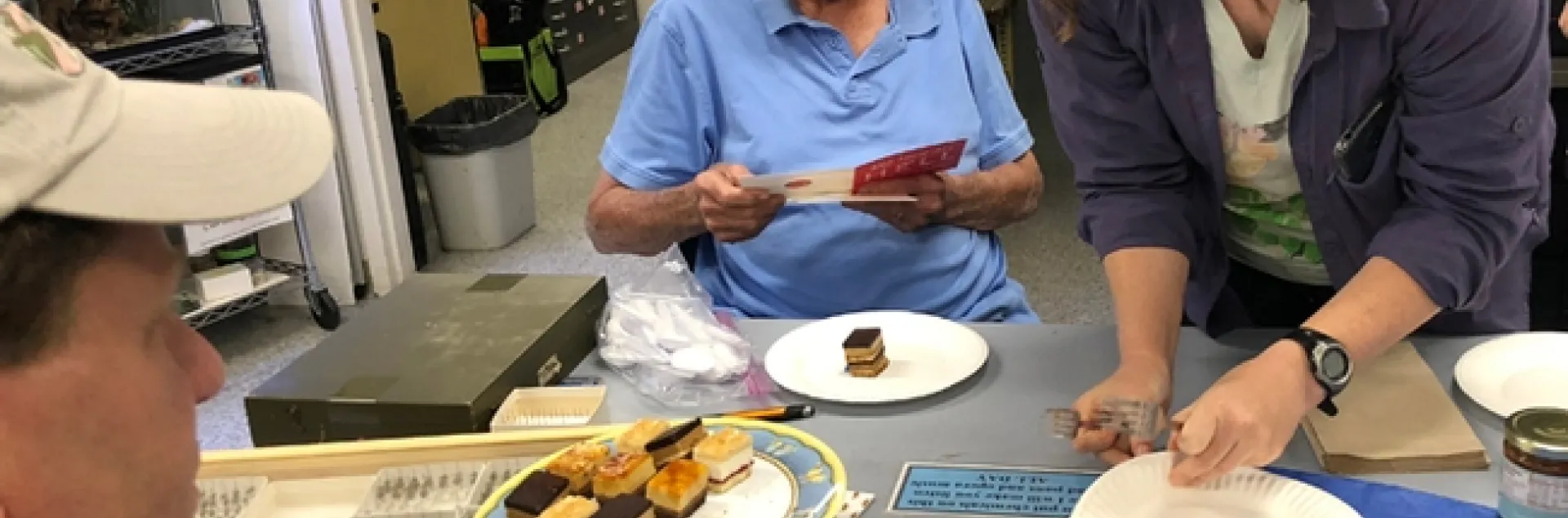Tabatha Yang, education and outreach coordinator for the Bohart Museum of Entomology, serves dessert at Robbin Thorp's birthday celebration while the distinguished emeritus professor reads the birthday wishes. (Photo by Kathy Keatley Garvey)