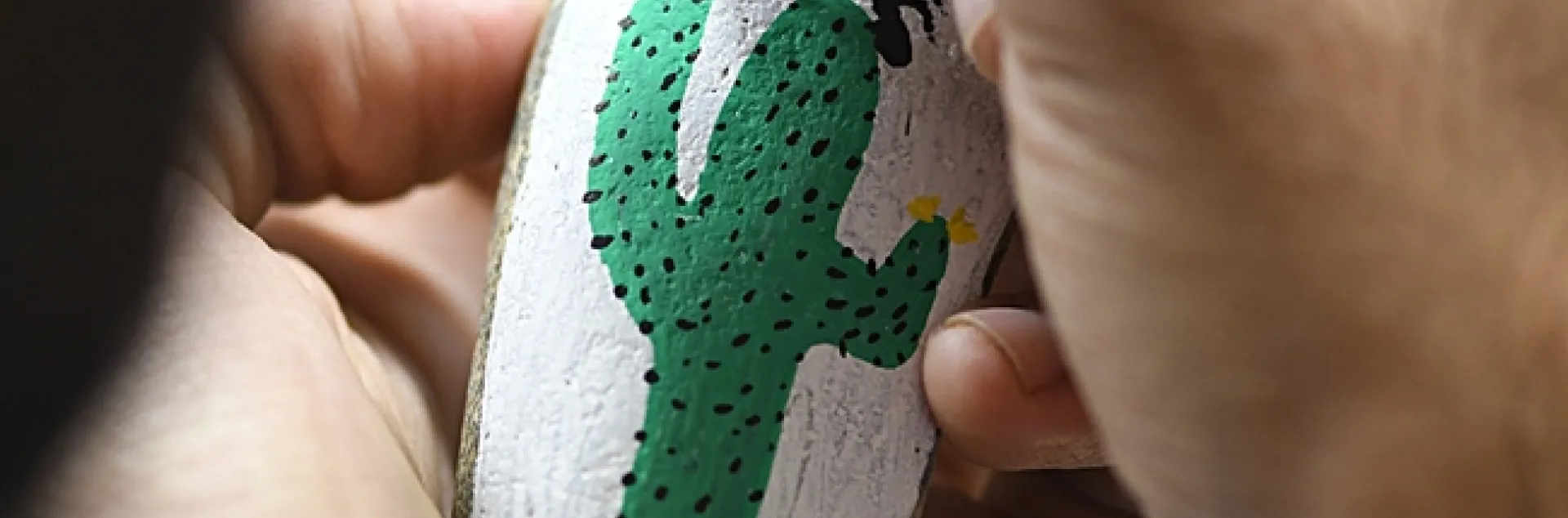 Entomologist Joel Hernandez adds the finishing touches on a rock painted by his wife, Melissa Cruz, the outreach coordinator for the UC Davis Arboretum and Public Garden. (Photo by Kathy Keatley Garvey)