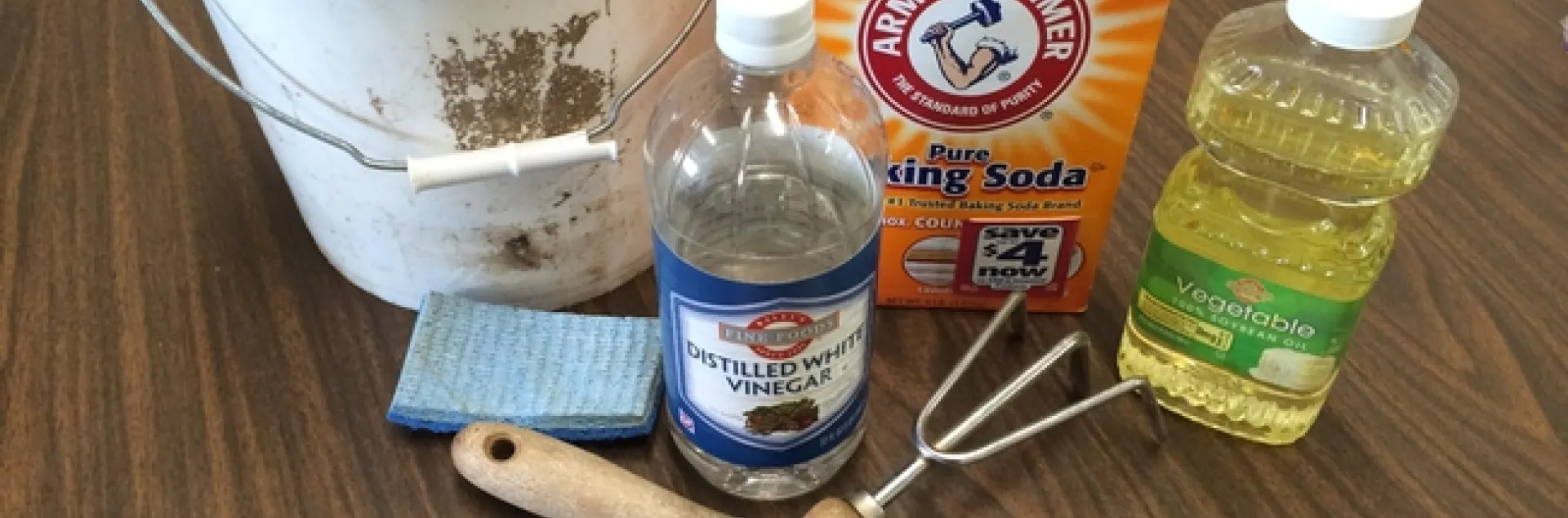 Baking soda, vinegar, vegetable oil, and a scrubber with garden tools.