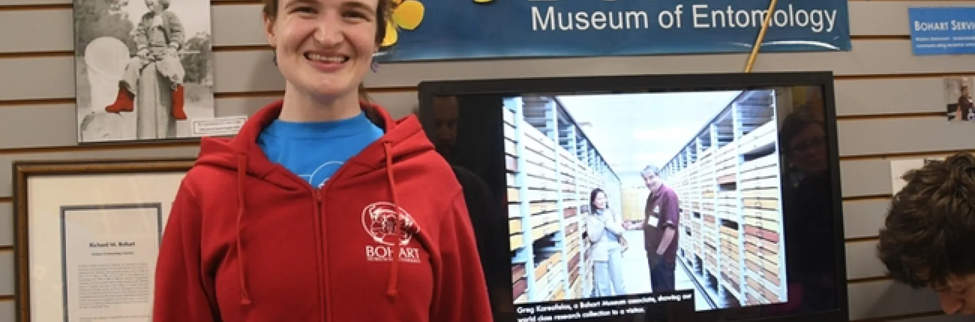 Entomologist/artist Charlotte Herbert Alberts wearing a red hooded sweatshirt: front view showing the Bohart logo and a tardigrade face. (Photo by Kathy Keatley Garvey)