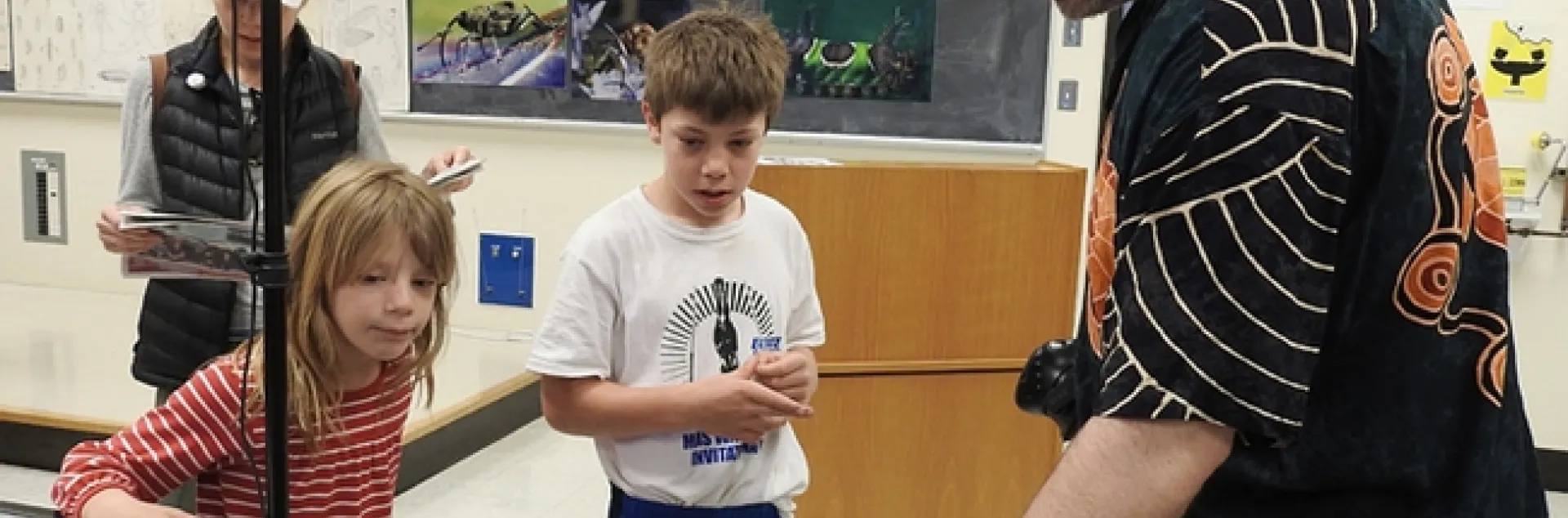 UC Davis medical entomologist Geoffrey Attardo shows Sebastian and Kamila Ehrlich examples of what insects they might want to see in virtual reality. In back is their mother, Carollina Ehrlich. (Photo by Kathy Keatley Garvey)