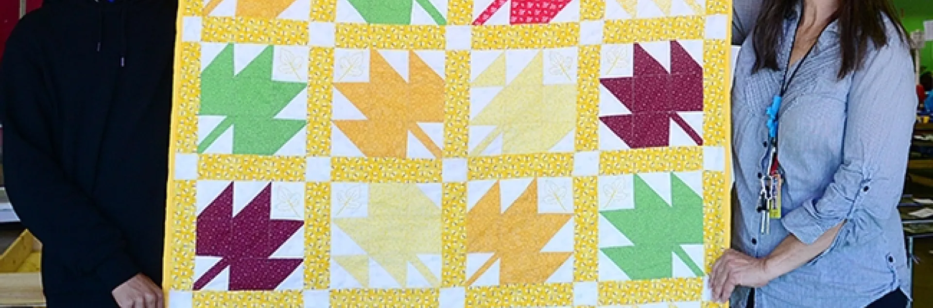 Gloria Gonzalez, superintendent of McCormack Hall at the Solano County Fair, holds a bee-themed quilt with assistant Jarod Fernander of Vallejo, 15, a student at the Pleasant Hill Adventist Academy. The quilt is the work of Tina Frothy of Vallejo. (Photo by Kathy Keatley Garvey)