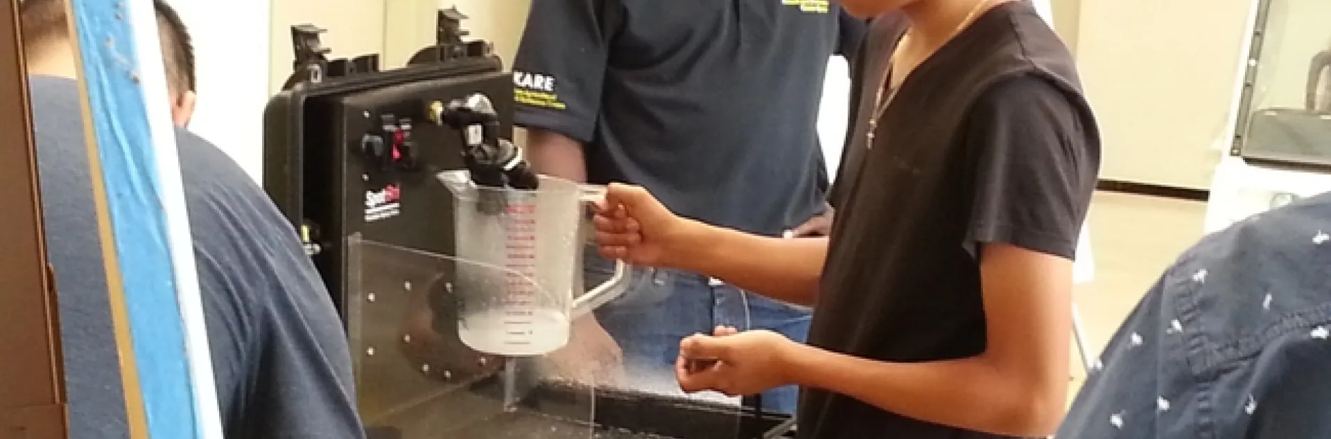 Dr.Peter Ako Larbi guides a student in measuring nozzle output volume per time, as affected by pressure.