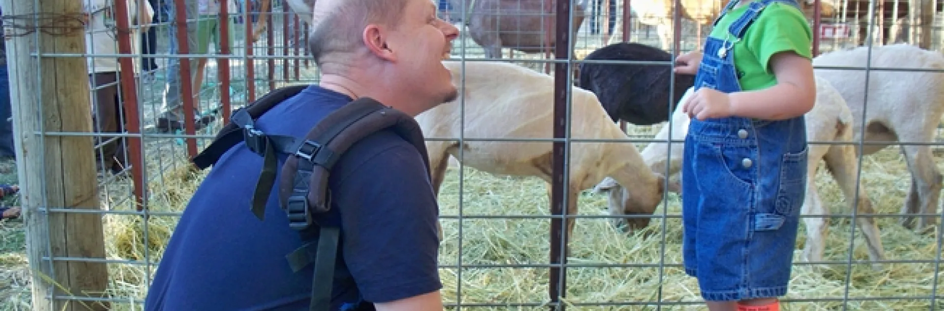 Father and son enjoy a petting zoo on a farm offering agritourism experiences.