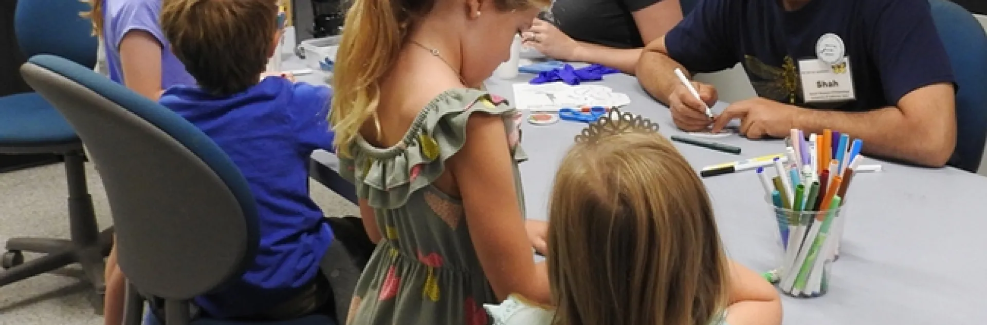 Visiting scholar Syed Fahad Shah and doctoral student Charlotte Herbert Alberts (next to him) help youngsters make buttons at the Bohart Museum of Entomology open house. (Photo by Kathy Keatley Garvey)