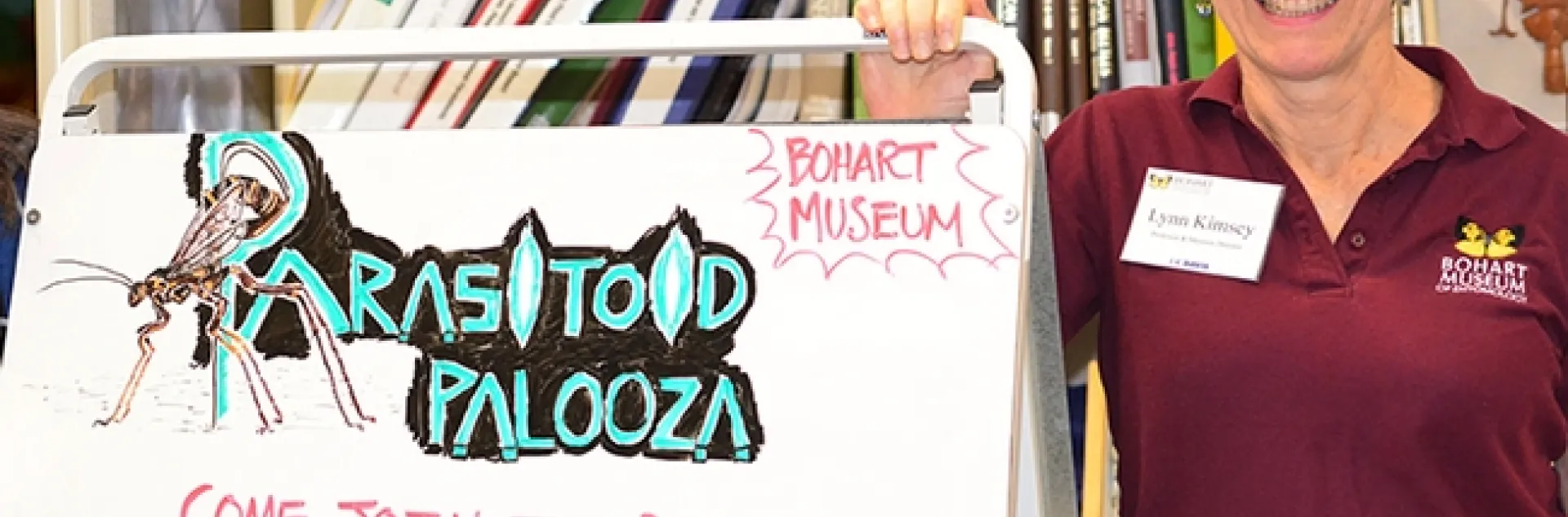 Lynn Kimsey, director of the Bohart Museum of Entomology, stands by a Parasitoid Palooza sign. (Photo by Kathy Keatley Garvey)