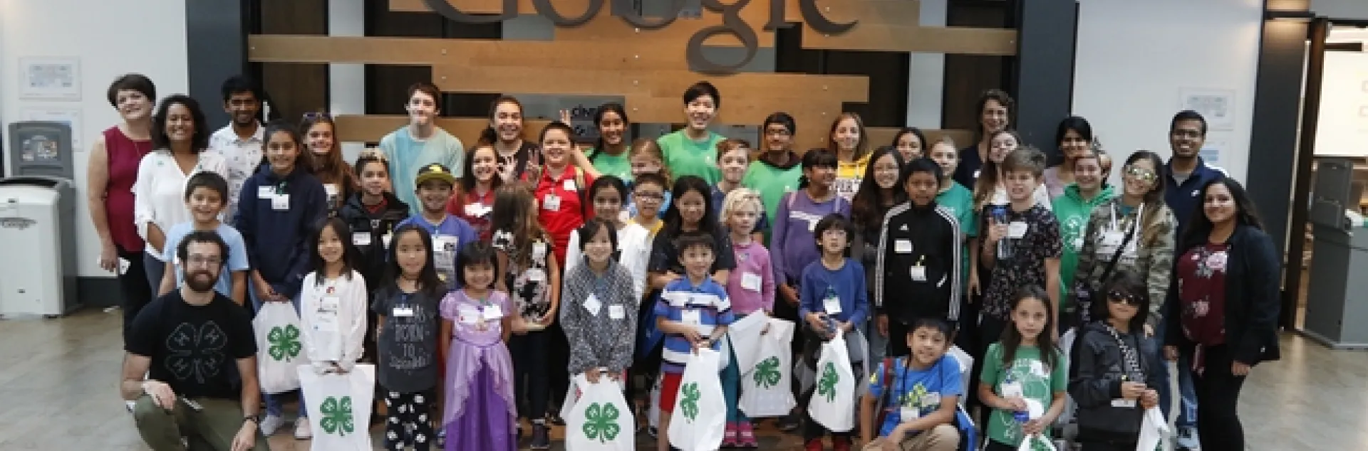 CS Pathway Team, volunteers, Googlers, and youth participants posing in front of a Google sign.