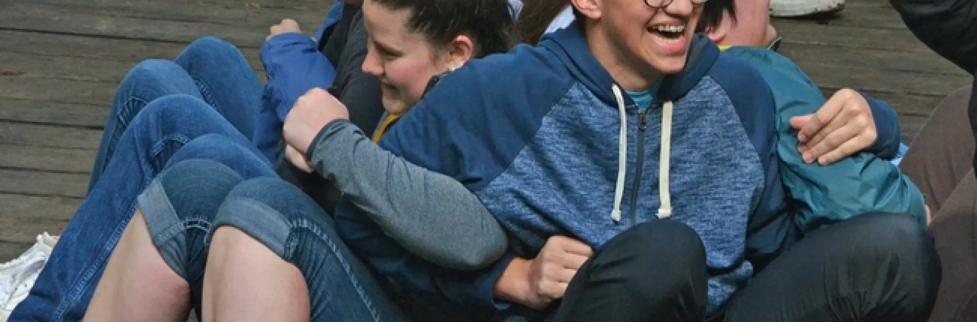 Group of youth linking arms and back to back in an activity