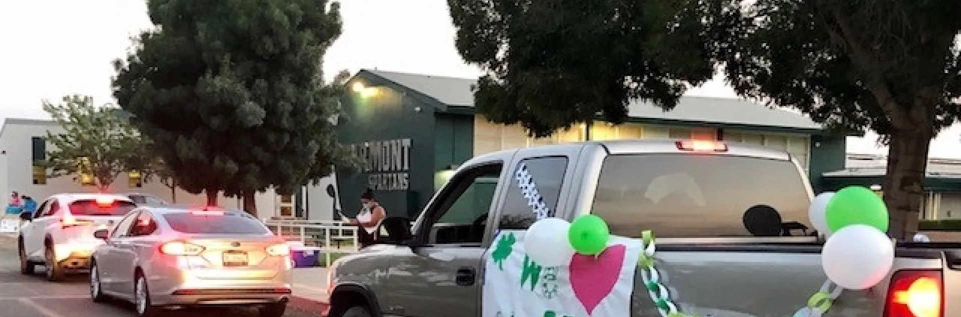 Cars and truck lined up. Truck is decorated with 4-H banner and balloons