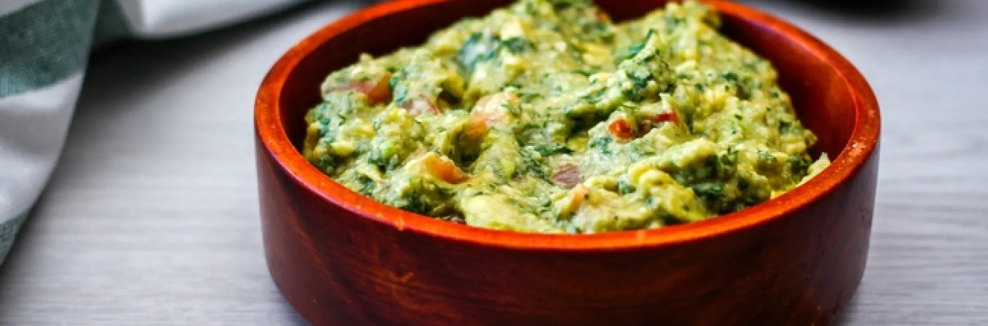 Bowl of guacamole with tortilla chips on the side.