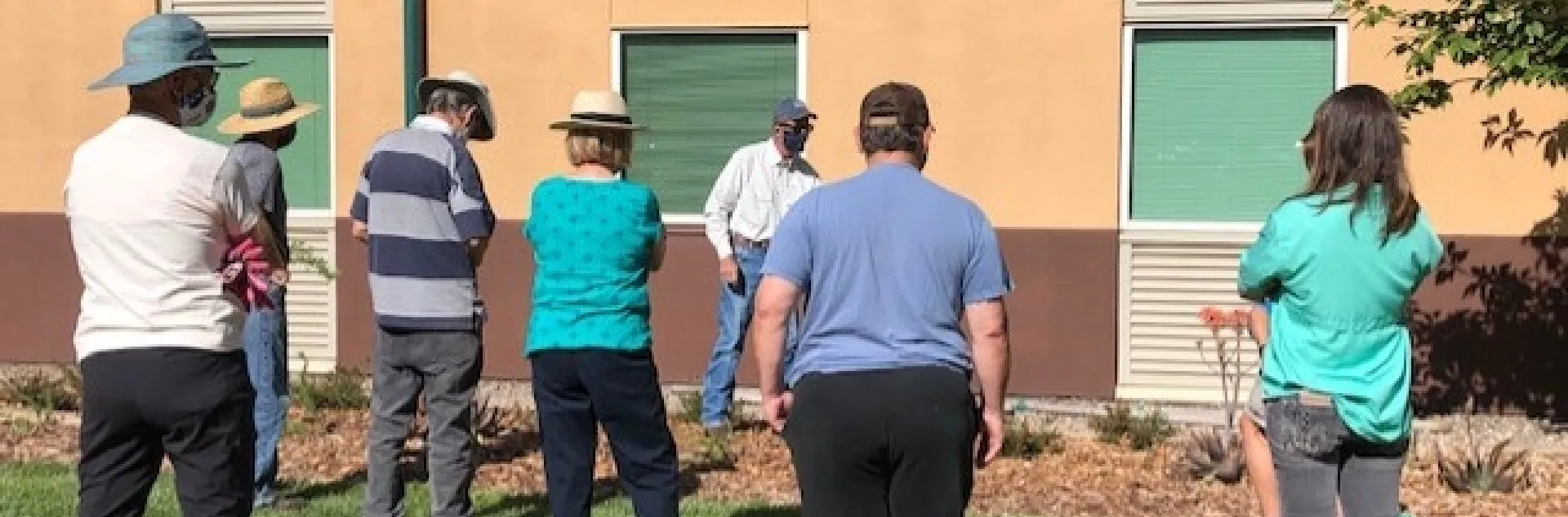 Six people facing an instructor giving a lesson about trees.