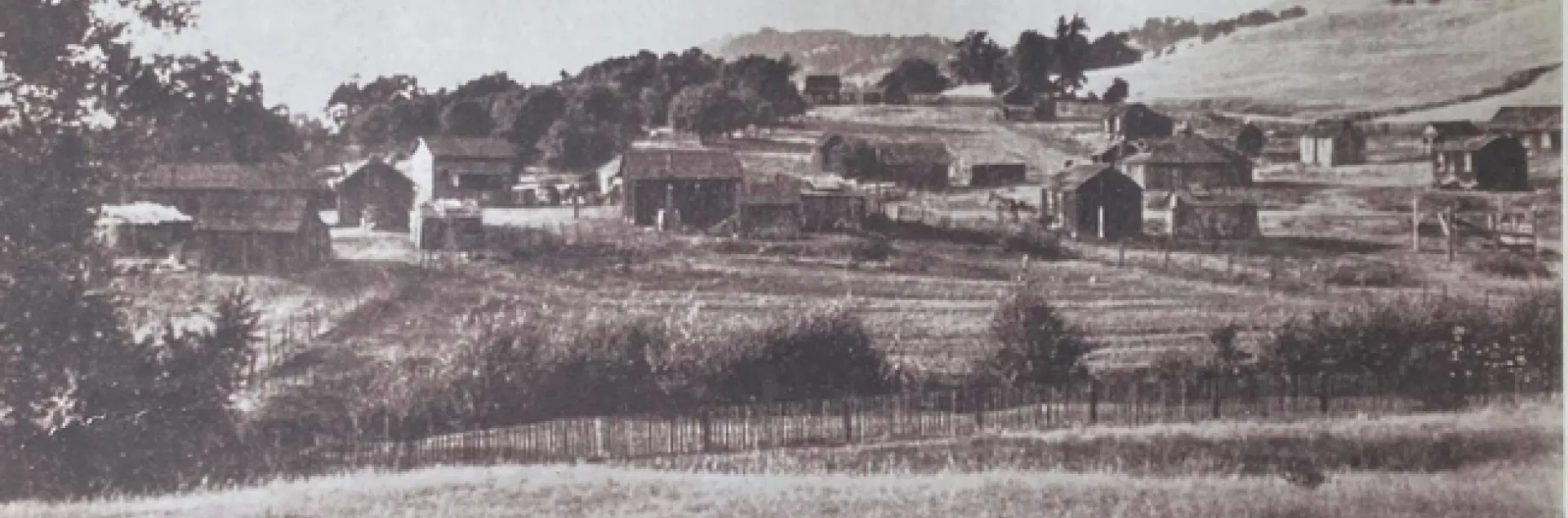 Sepia-tone image of one-story structures.
